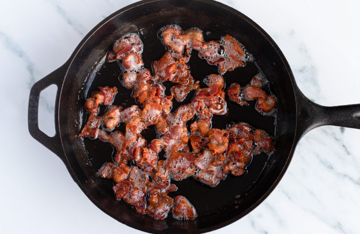 sizzling cooked bacon in cast iron skillet
