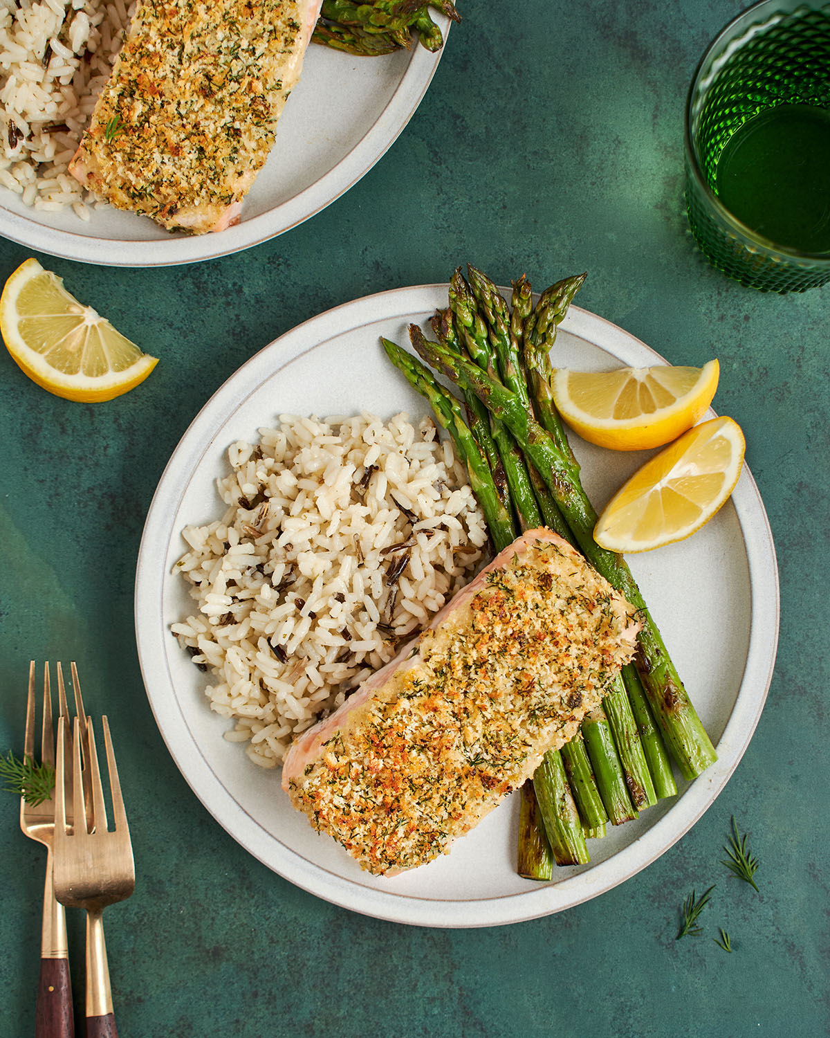 baked salmon on dinner plate with rice, asparagus, and lemon wedges