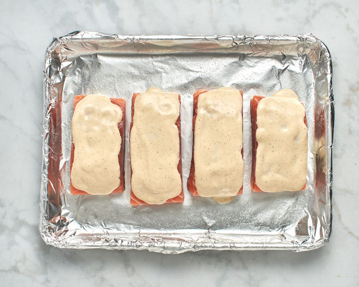 salmon fillets on foil-lined baking sheet topped with mayo mixture