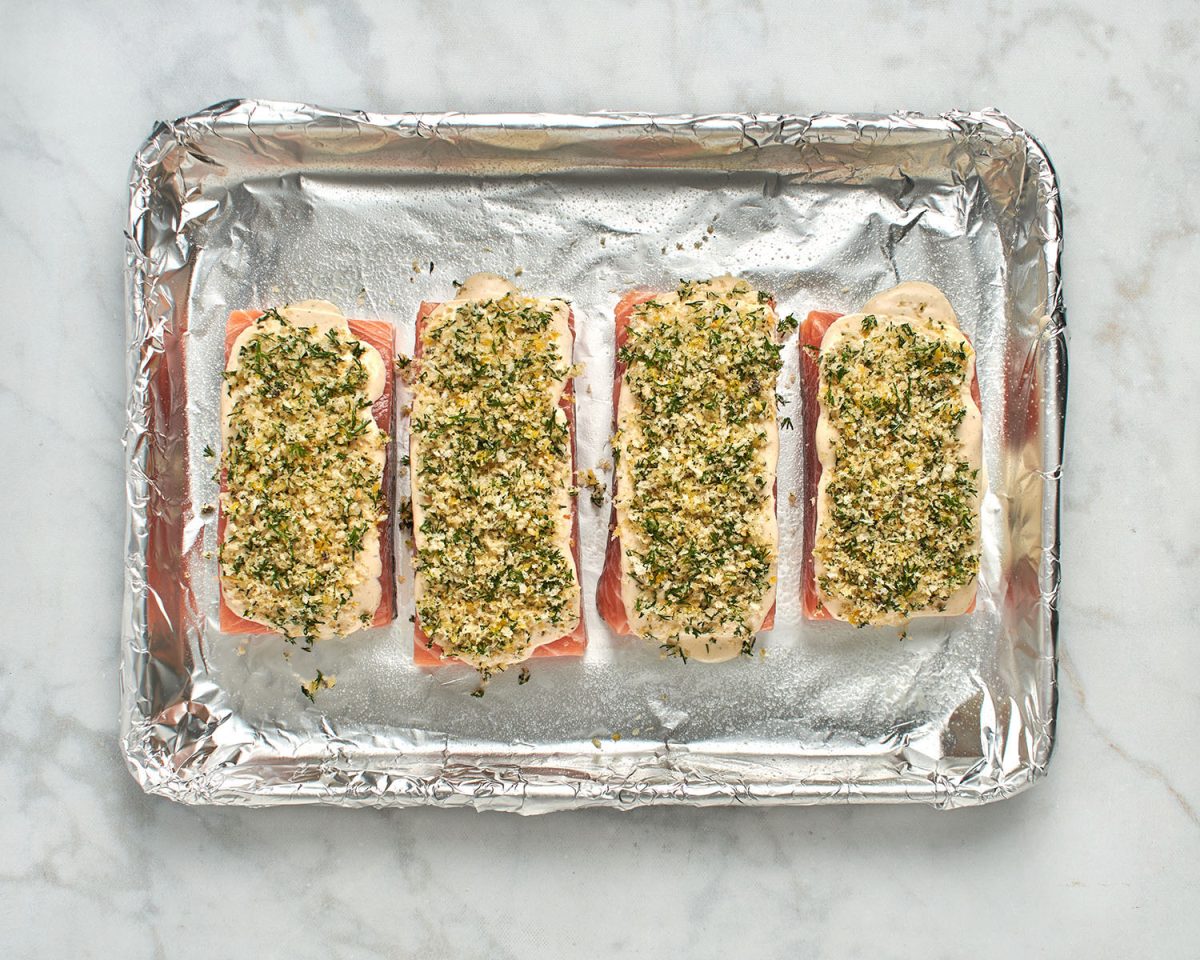 salmon fillets on foil-lined baking sheet topped with mayo mixture and panko dill topping