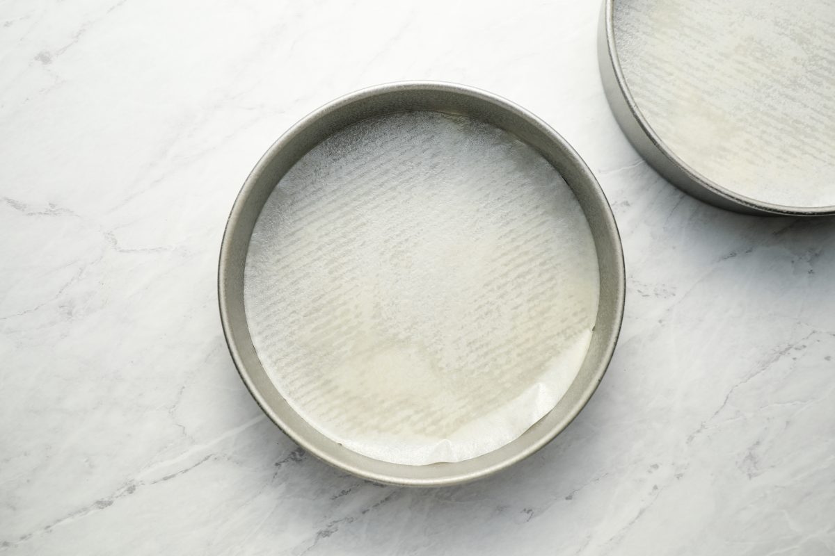 parchment lined cake pans on marble board.
