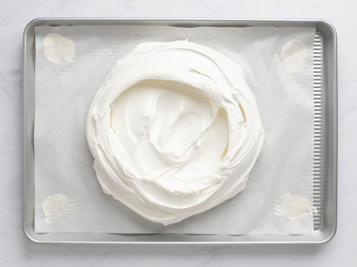 meringue portion of pavlova on parchment-lined baking sheet with center slightly indented