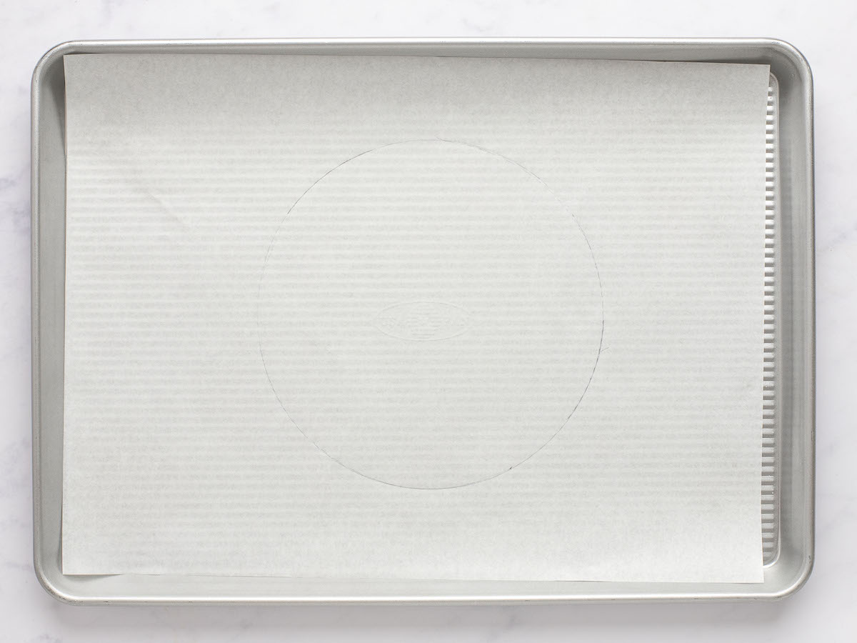 parchment on baking sheet flipped over with 9-inch circle showing through other side