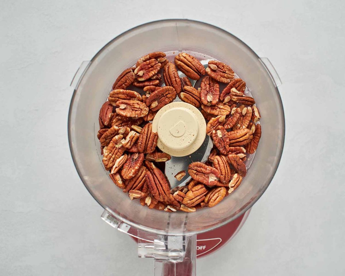 pecans in the bowl of a food processor.