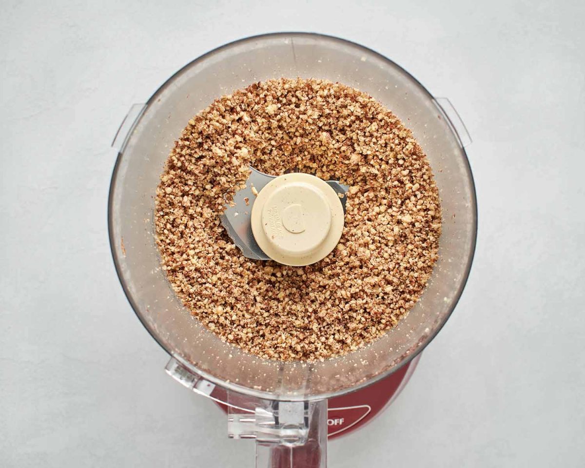 blended pecans in the bowl of a food processor.
