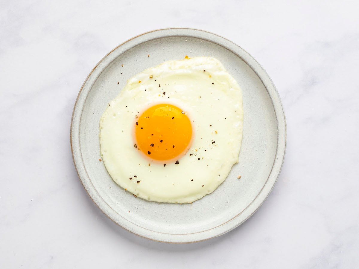 sunny side up egg on white plate with salt and pepper