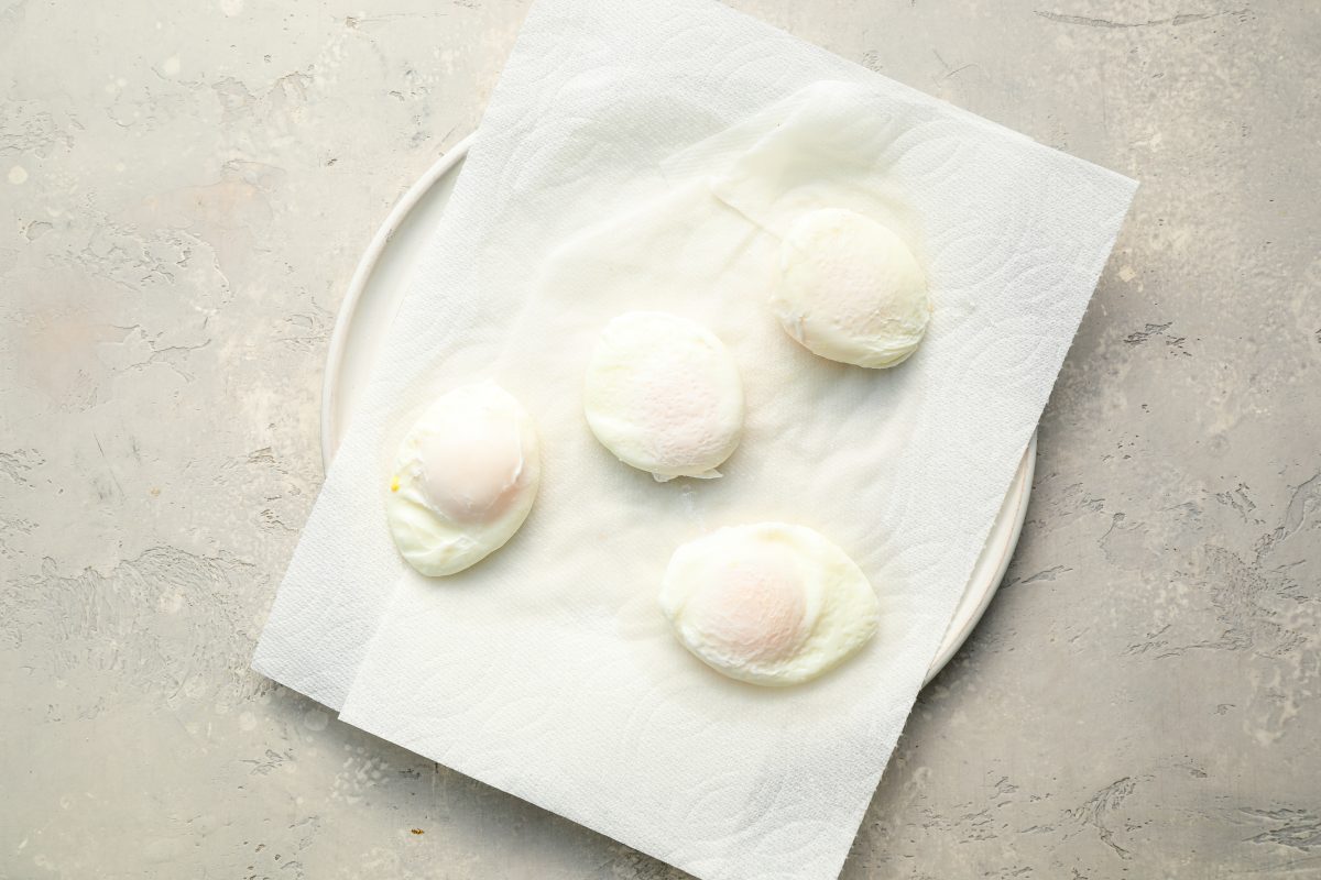 poached eggs draining on paper towel-lined plate