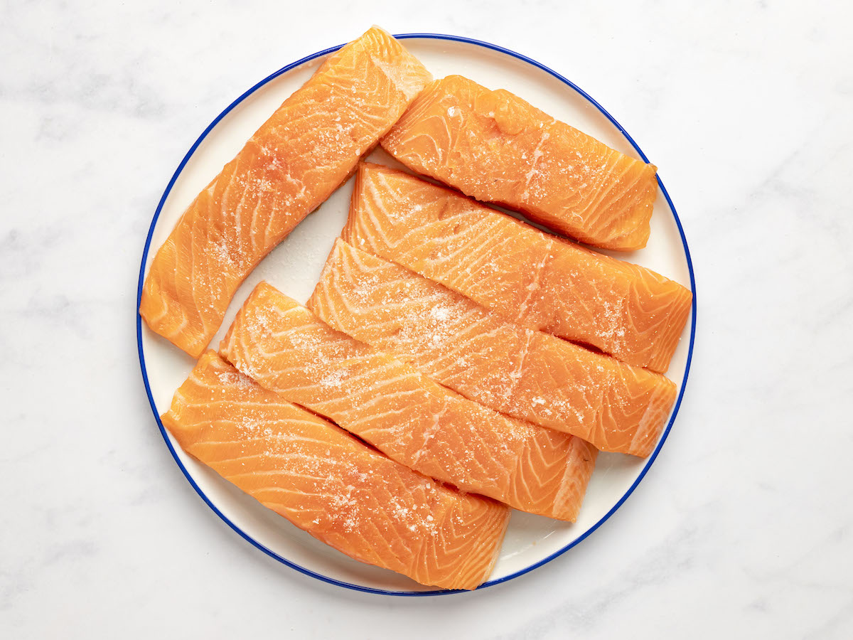 seasoned salmon fillets on white plate.