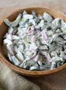 creamy cucumber salad in wooden bowl.