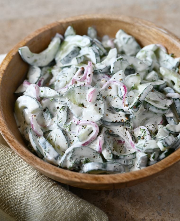 creamy cucumber salad in wooden bowl.