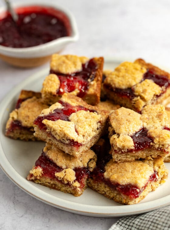 raspberry bars stacked on white platter.
