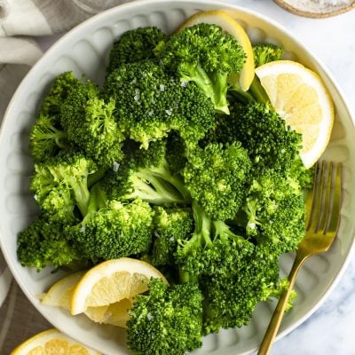 steamed broccoli in bowls with lemon wedges
