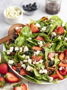 bowl of spinach salad with berries, pecans, goat cheese and raspberry vinaigrette