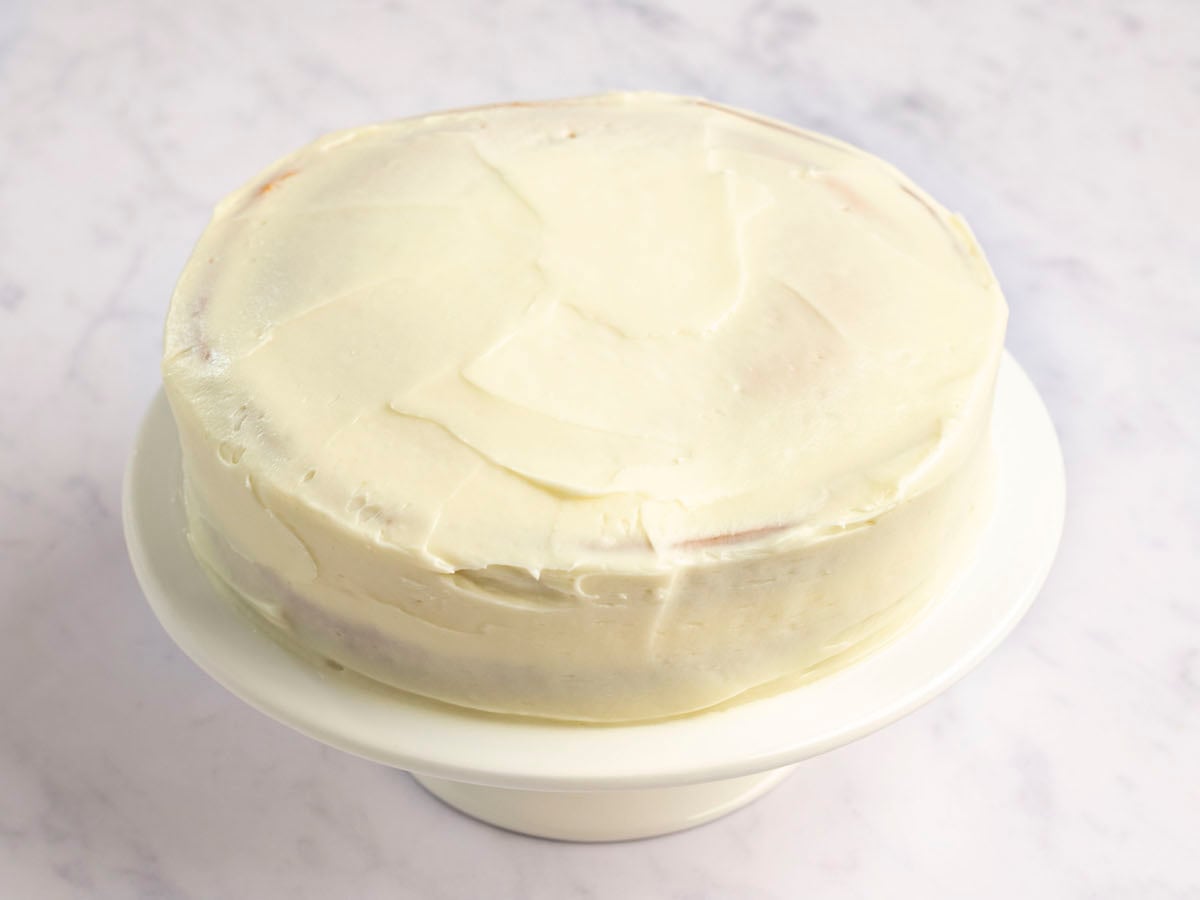 cake on white cake plate fully covered with frosting