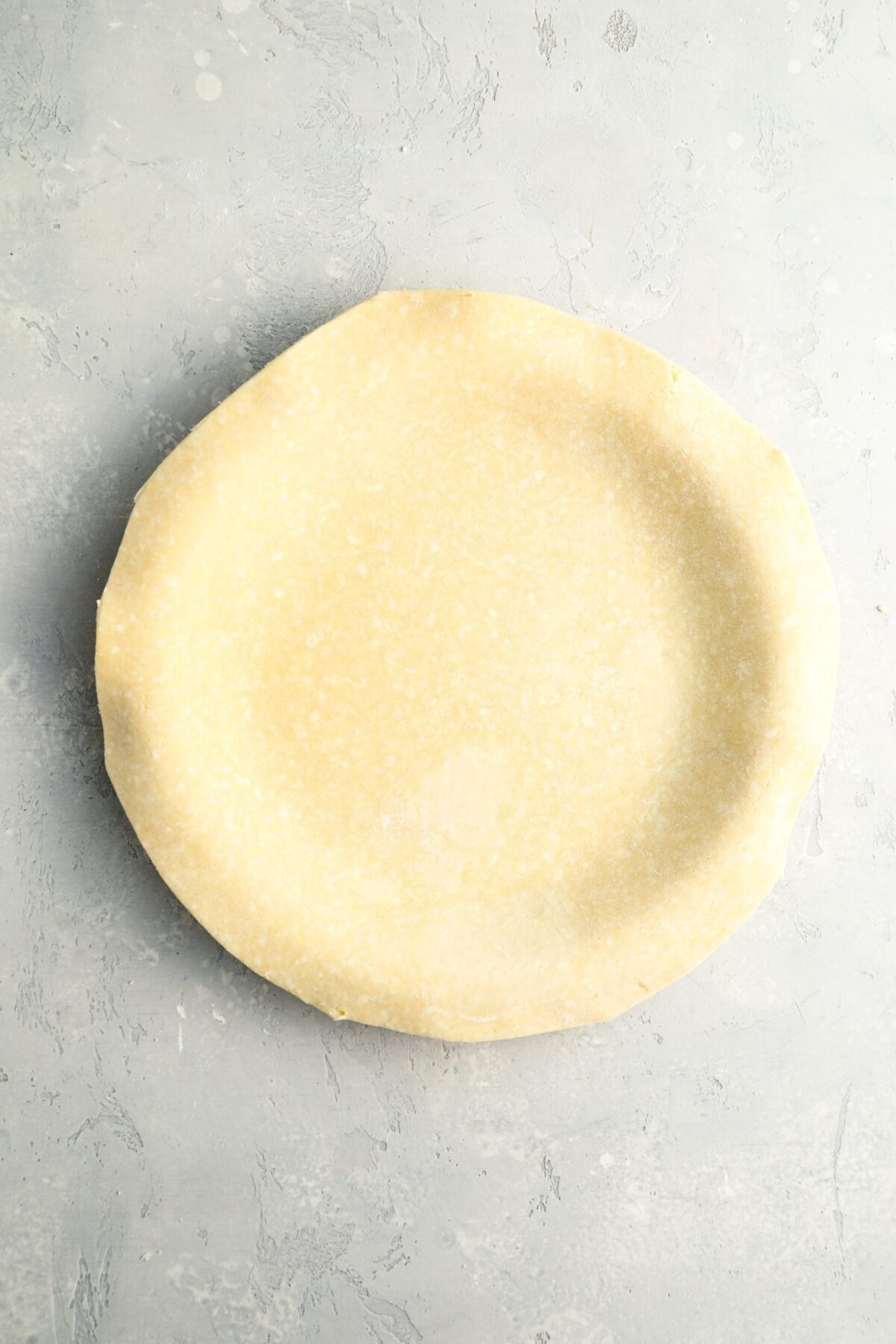 dough pressed into pie pan with edges trimmed