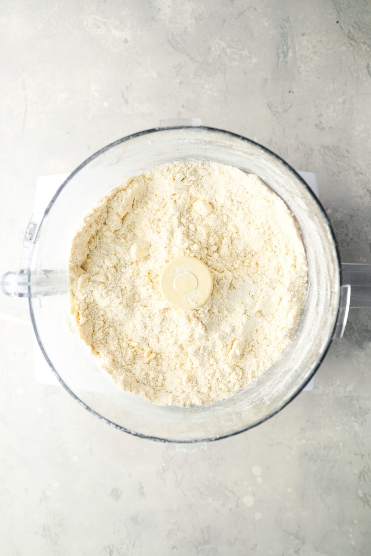 butter added to flour, sugar, salt, and baking powder in bowl of food processor