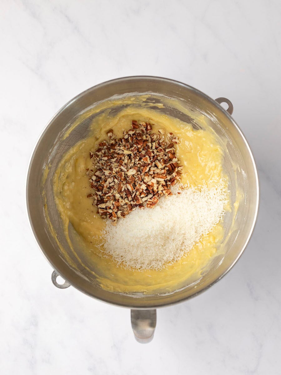 coconut and pecans added to batter in metal mixing bowl