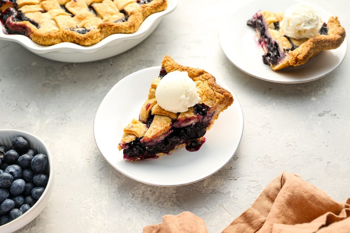Slice of blueberry pie topped with vanilla ice cream.