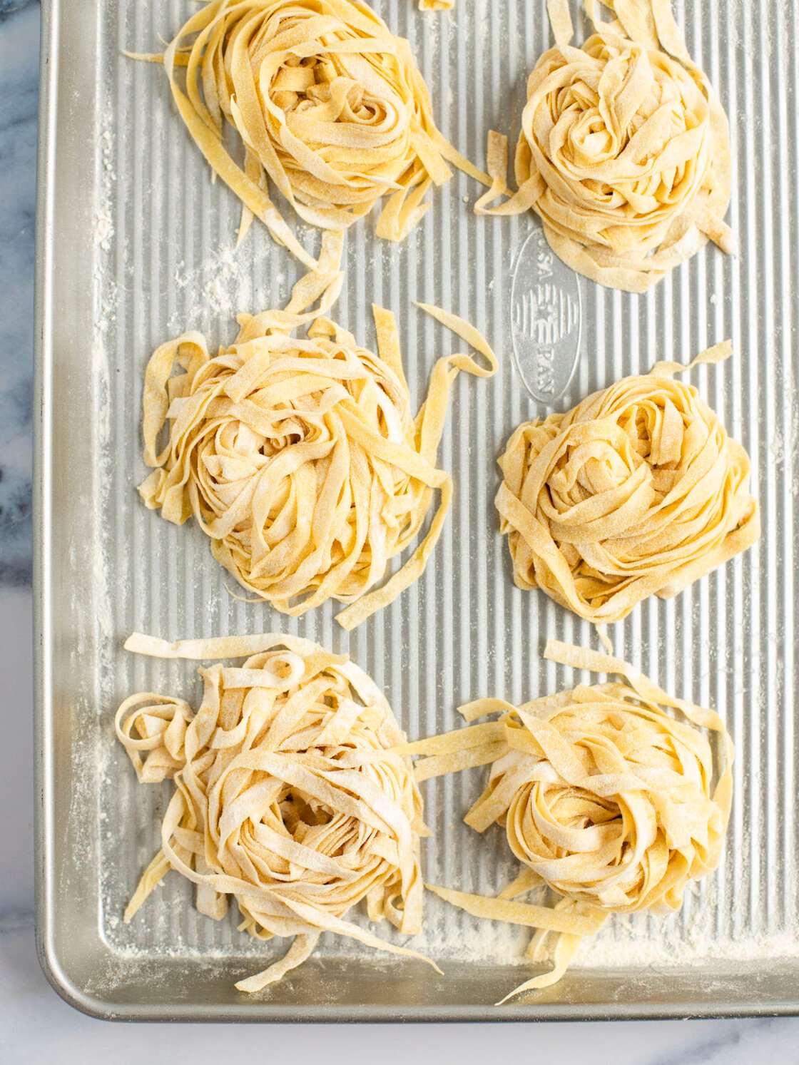 nests of homemade pasta on baking sheet.