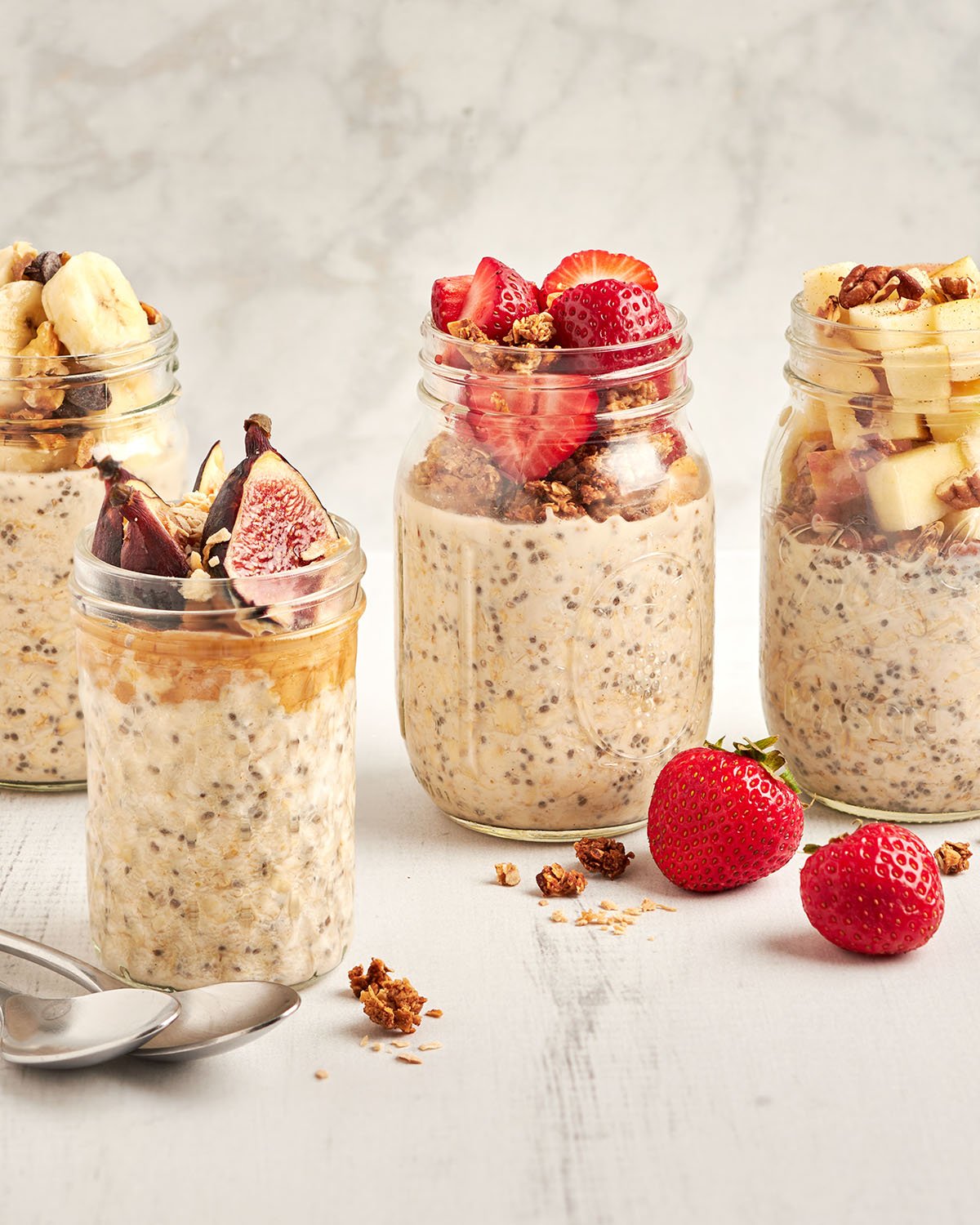 4 jars of overnight oats topped with a variety of fresh fruit and granola