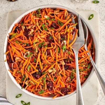 carrot slaw with cranberries, walnuts, and citrus vinaigrette in serving bowl.