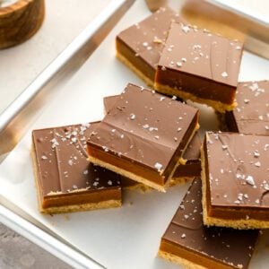 millionaire's shortbread bars on baking sheet with bowl of flaky sea salt.