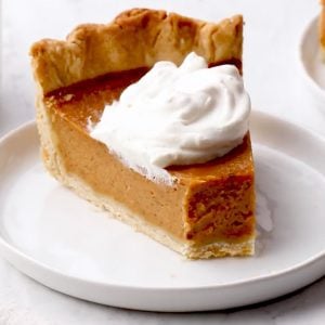Slice of pumpkin pie on a plate with a fork.