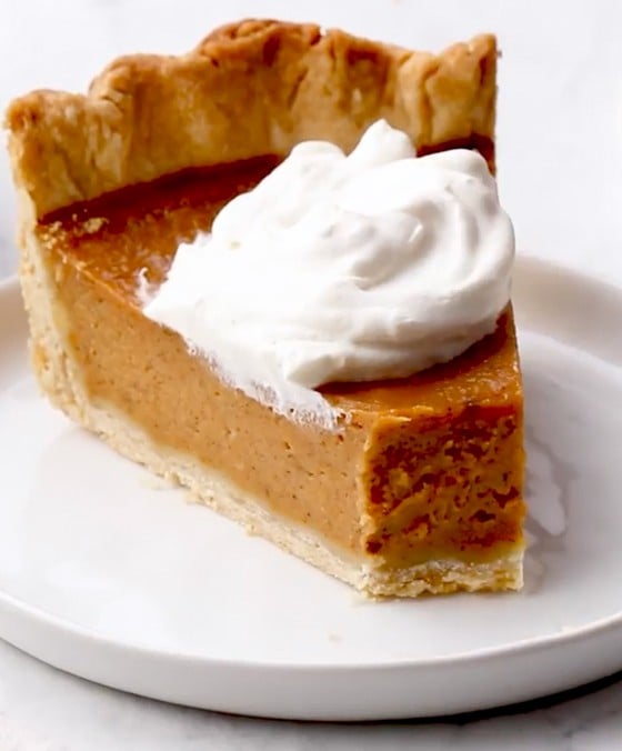 Slice of pumpkin pie on a plate with a fork.