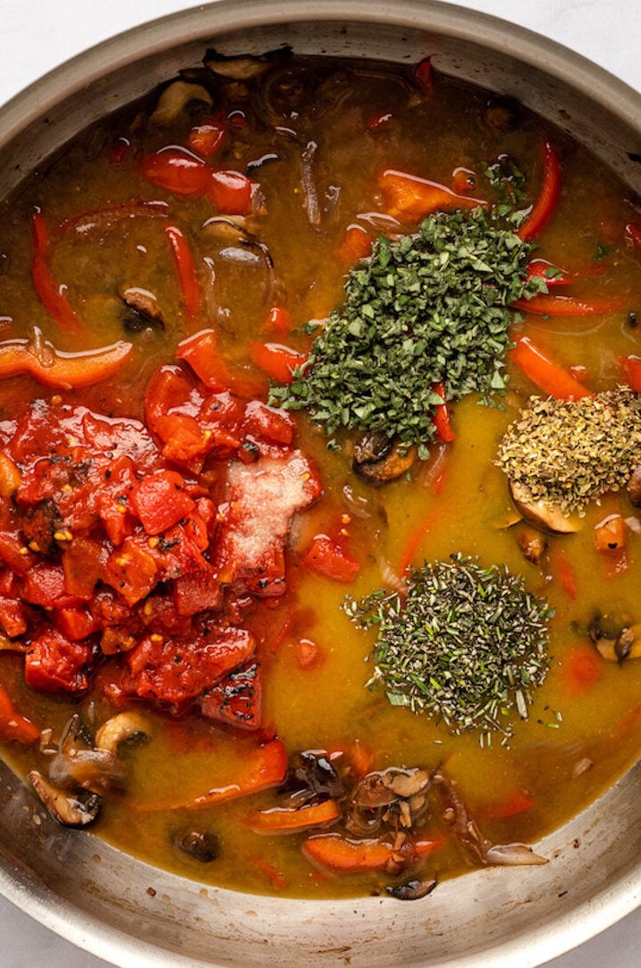broth, tomatoes, herbs in skillet with vegetables for chicken cacciatore sauce.