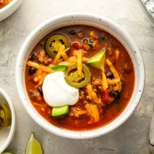 taco soup in bowl topped with cheese and sour cream
