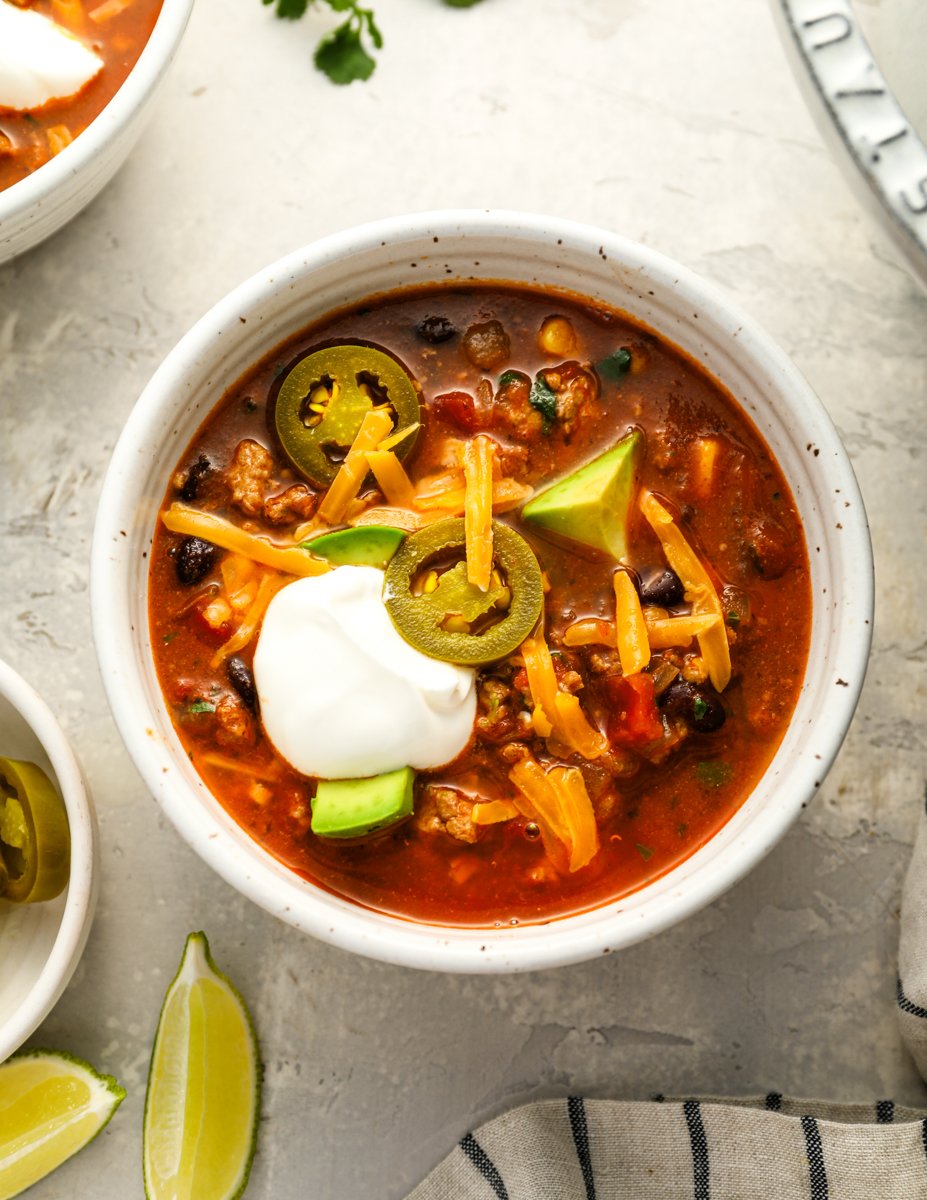 taco soup in bowl topped with cheese and sour cream