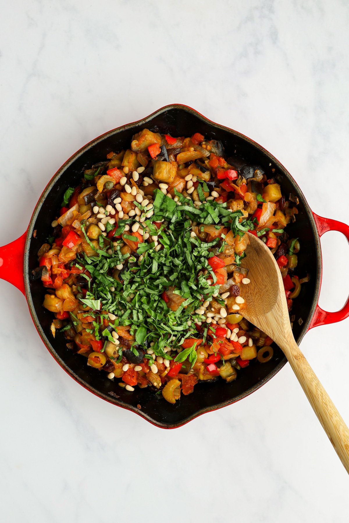 caponata in large skillet with basil and pine nuts on top