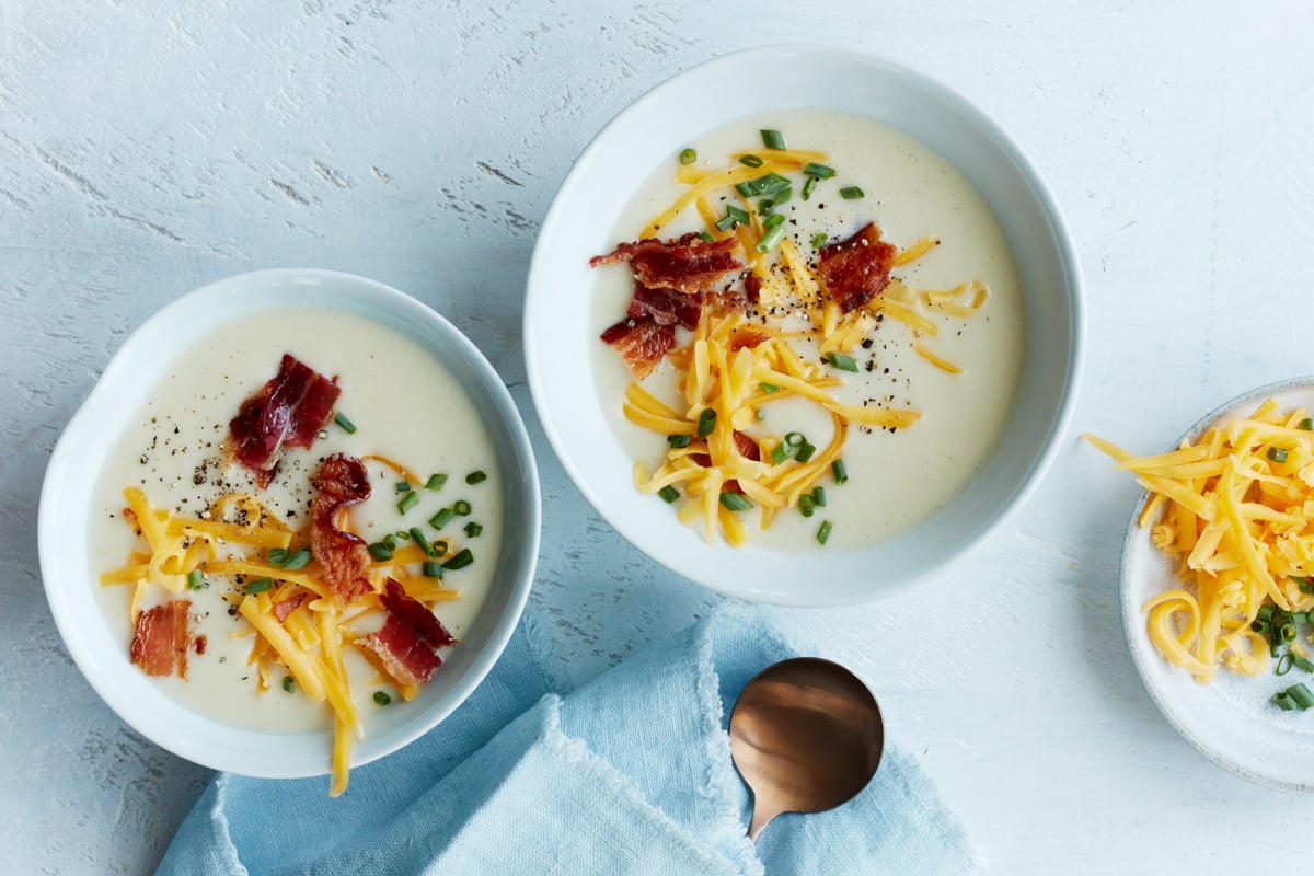 two bowls of creamy potato soup with toppings