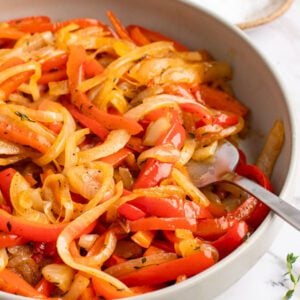 onions and peppers in bowl with salt, pepper, and thyme on side
