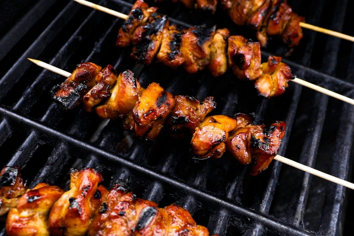 cooked, slightly charred chicken skewers on grill