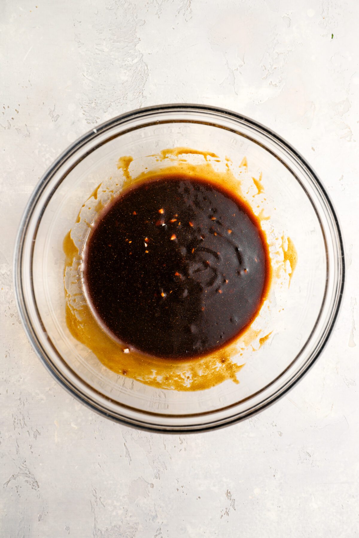 large glass bowl with soy sauce, oil, brown sugar, ketchup, garlic, turmeric, and coriander combined