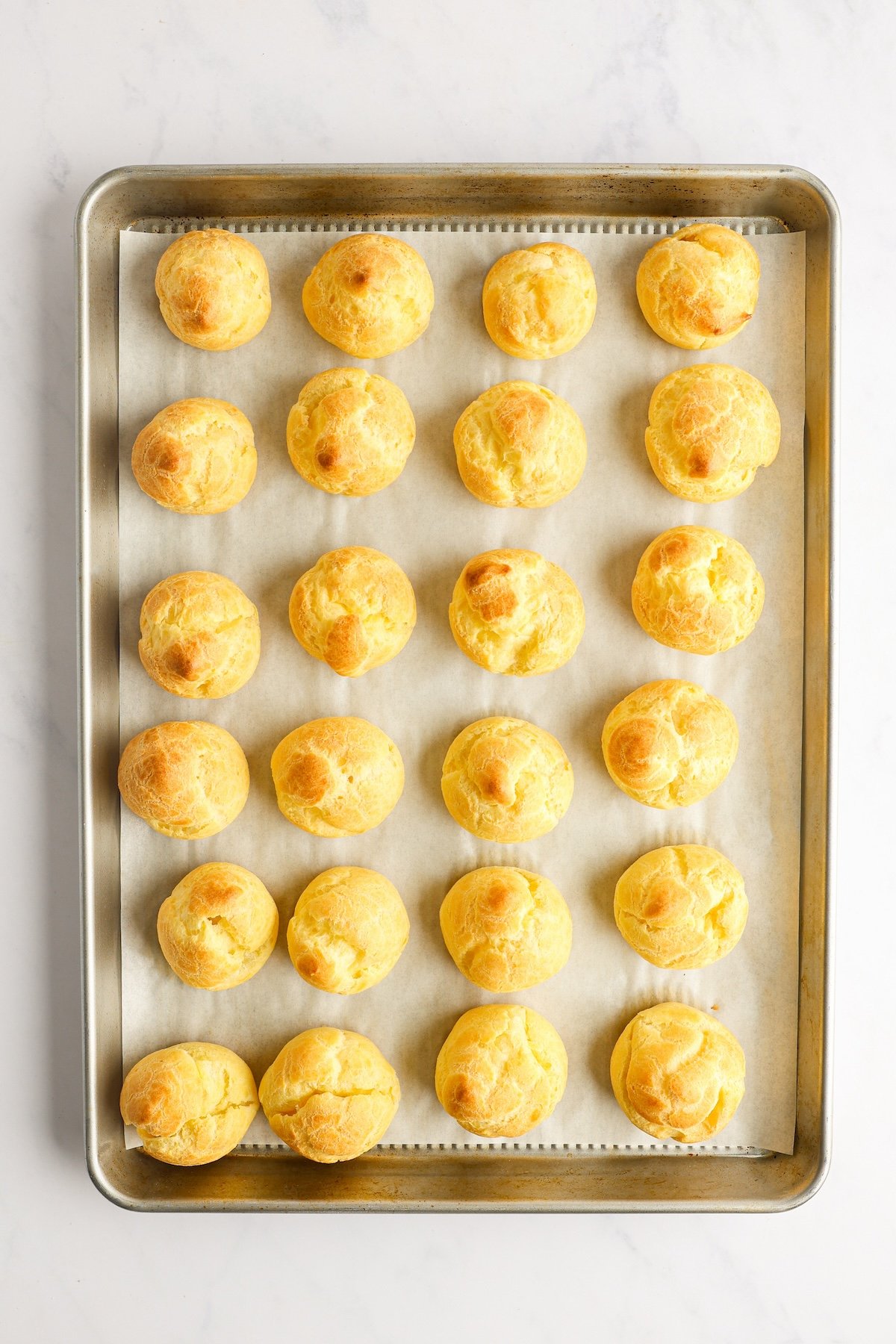 golden baked pastry shells on parchment-lined baking sheet