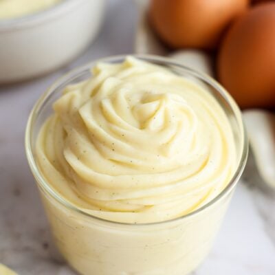 Vanilla pastry cream in bowl with eggs in the background.