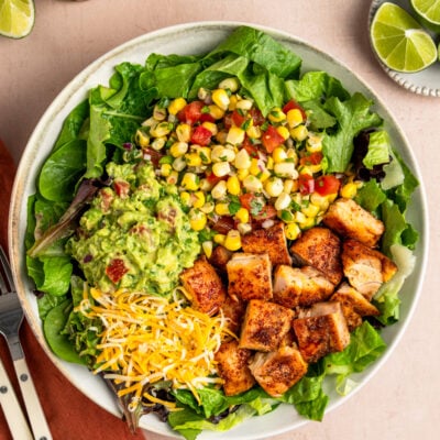 Copycat chipotle chicken in bowl with greens, corn salsa, guacamole and cheese.