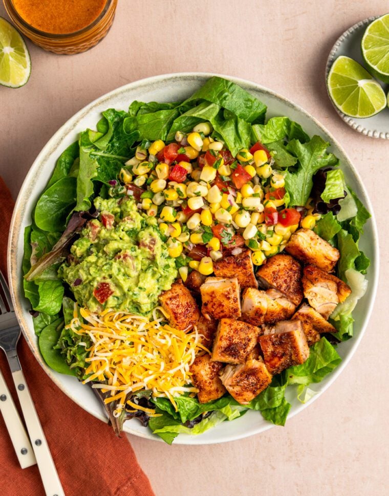 Copycat chipotle chicken in bowl with greens, corn salsa, guacamole and cheese.