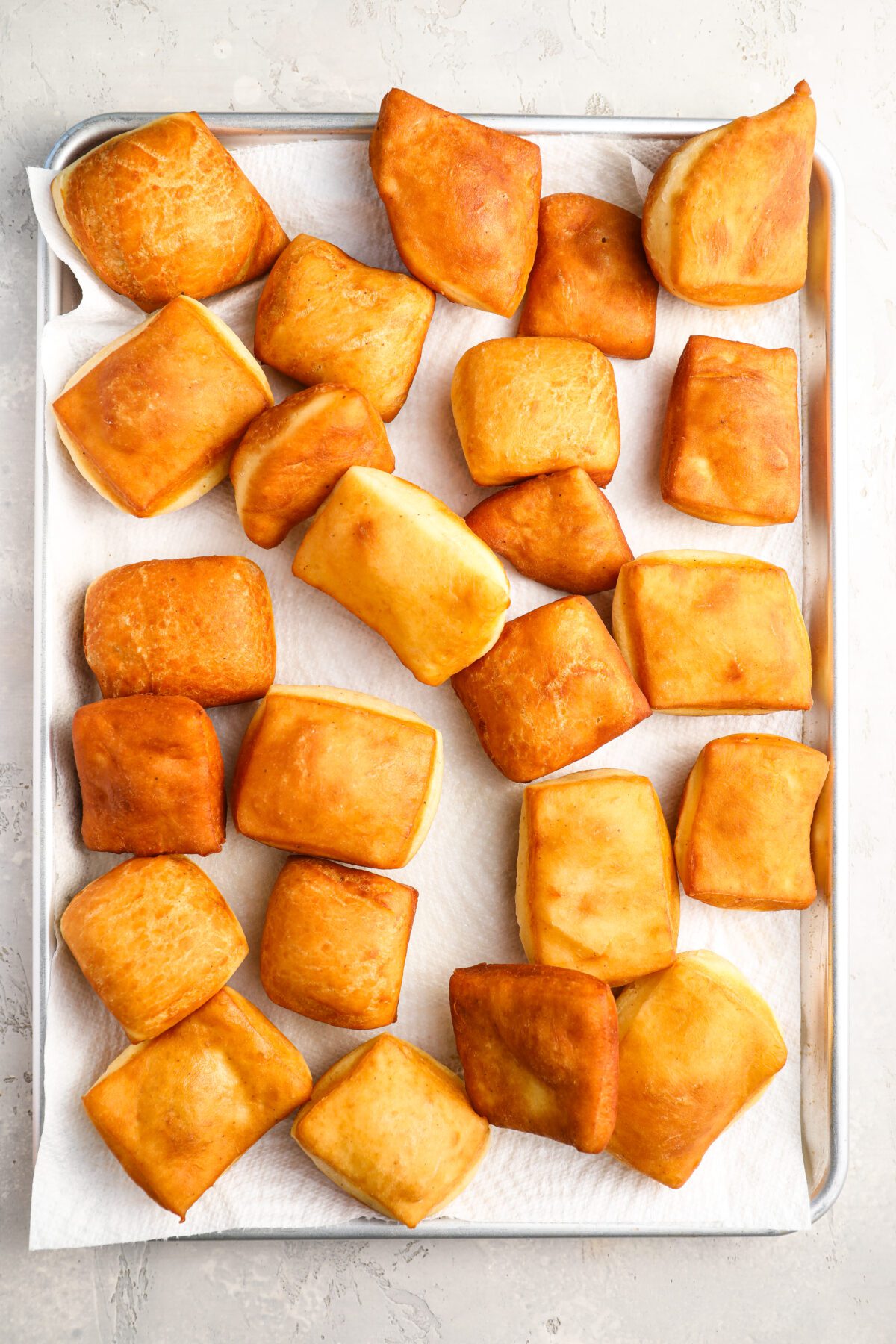 golden-brown beignets on paper towel-lined baking sheet