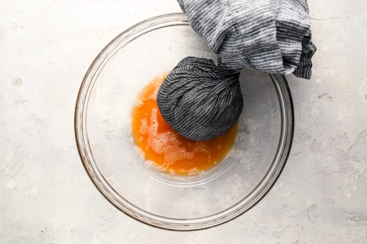 grated potatoes in a towel with excess liquid squeezed into bowl