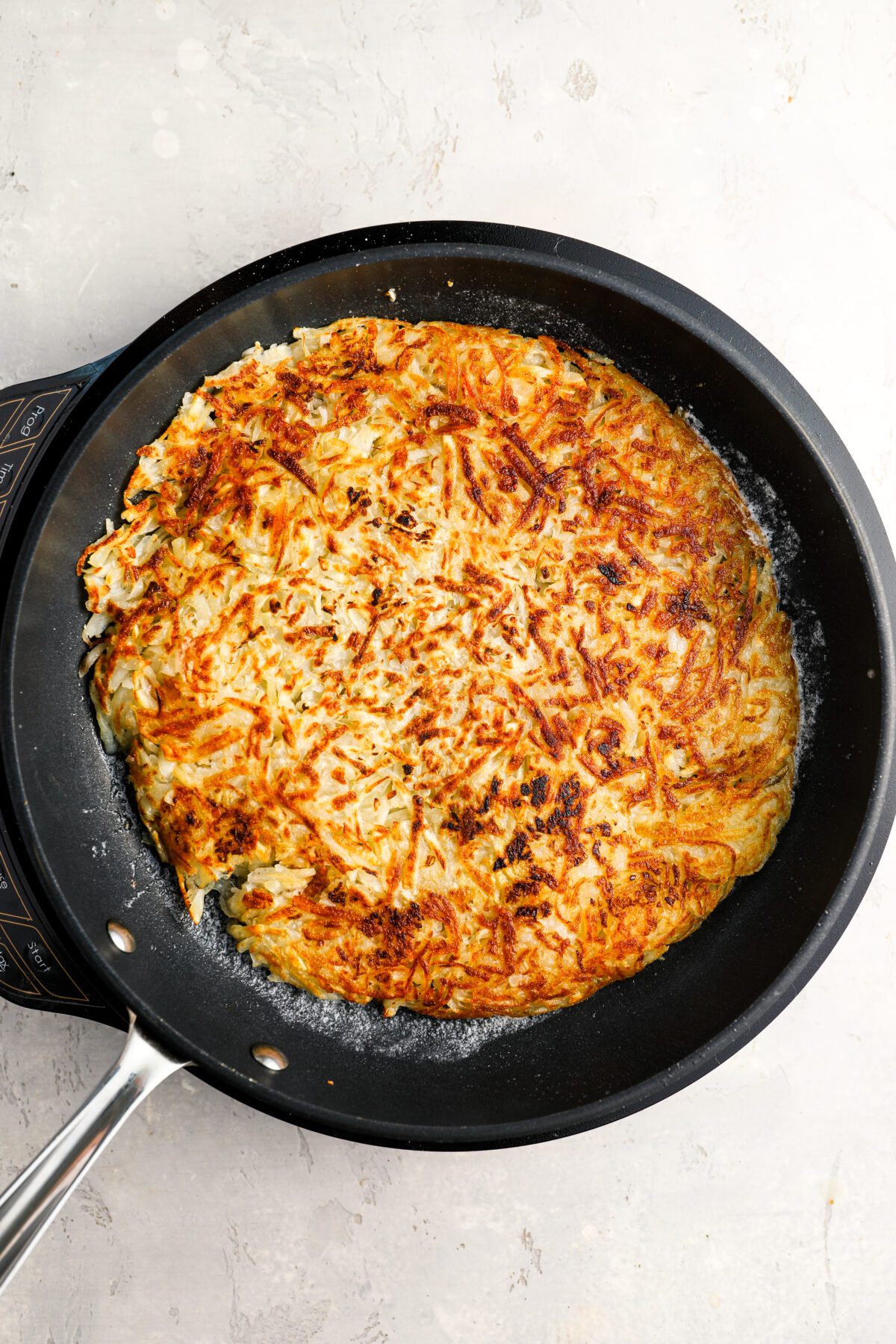 hash browns in cast iron skillet with cooked side up