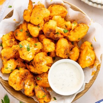 buffalo cauliflower bites in napkin lined basket with ramekin of blue cheese dressing