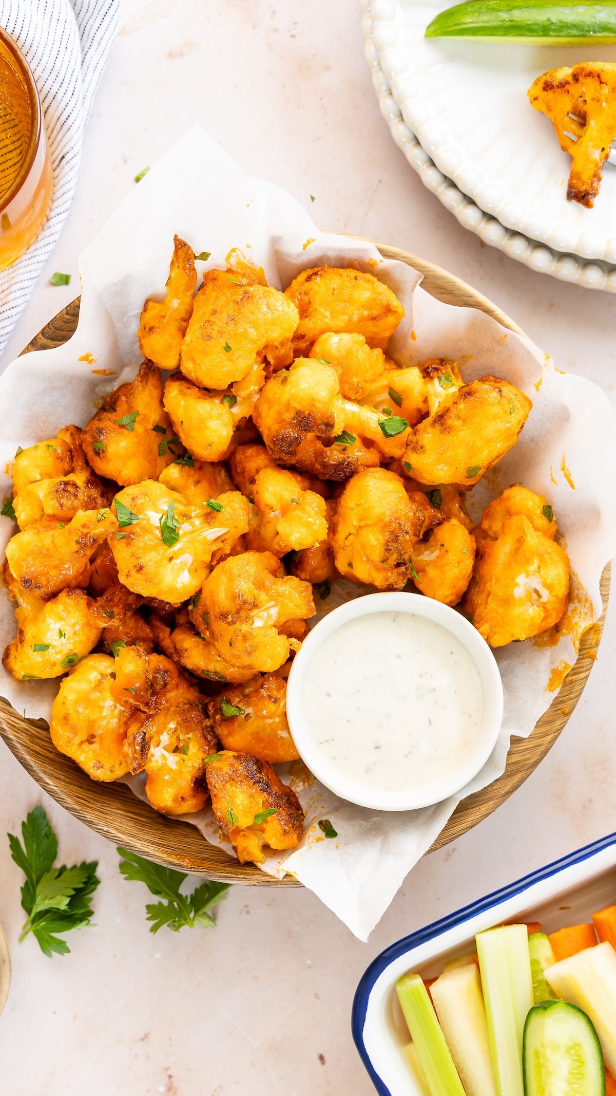 buffalo cauliflower bites in napkin lined basket with ramekin of blue cheese dressing