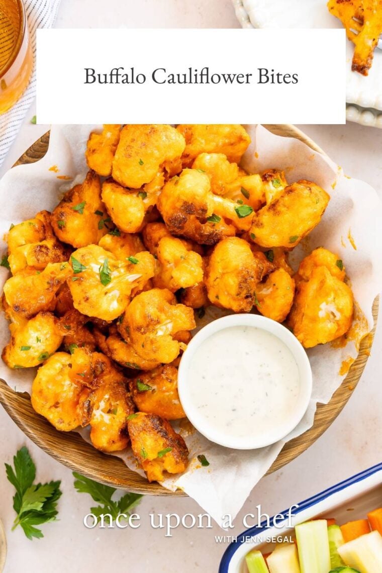 buffalo cauliflower bites in a paper towel lined basket with ramekin of blue cheese dressing