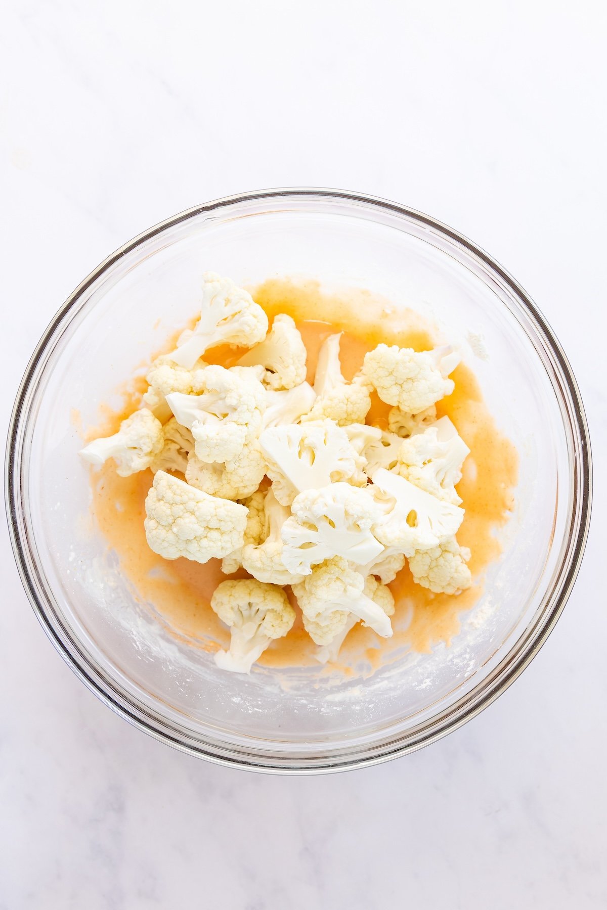 large bowl with cauliflower florets added to batter