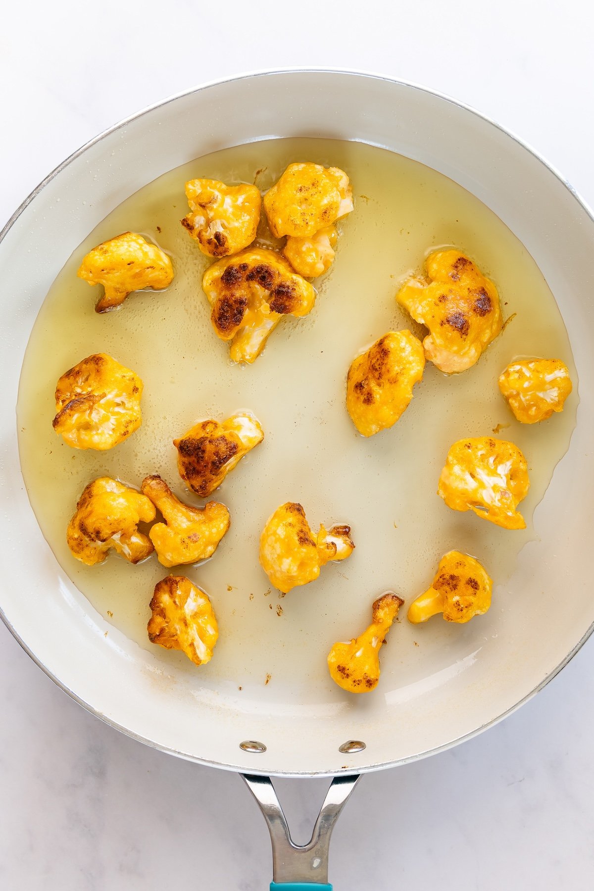 skillet with oil and portion of battered cauliflower 