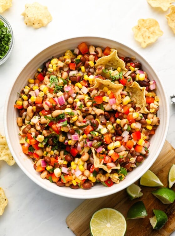 cowboy caviar in serving bowl with chips, cilantro and lime