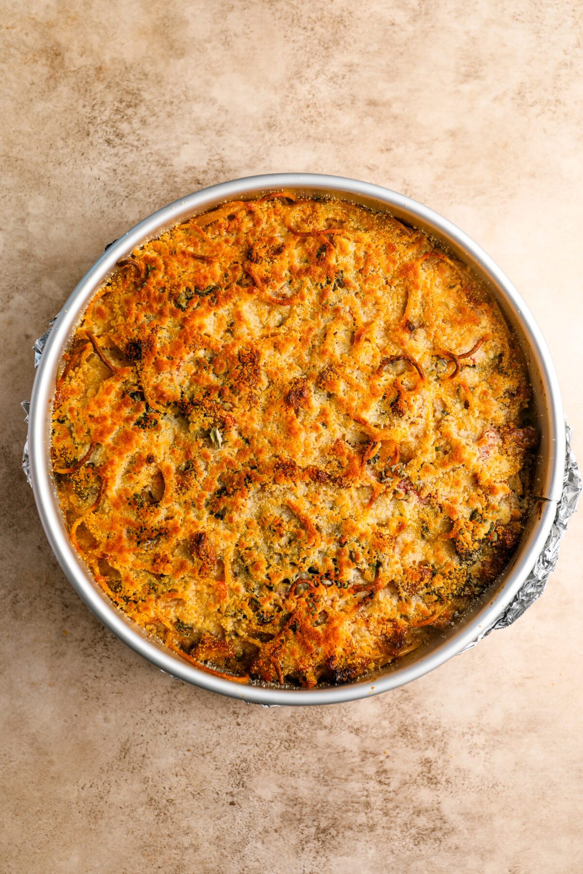 springform pan with baked spaghetti pie with browned parmesan topping